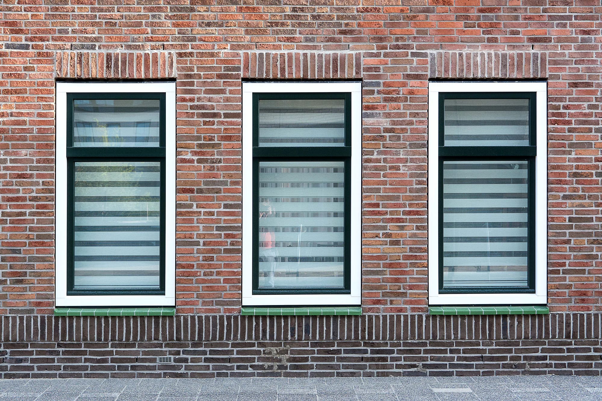 Witte kunststof kozijnen met isolerend glas in een Nederlandse bakstenen gevel