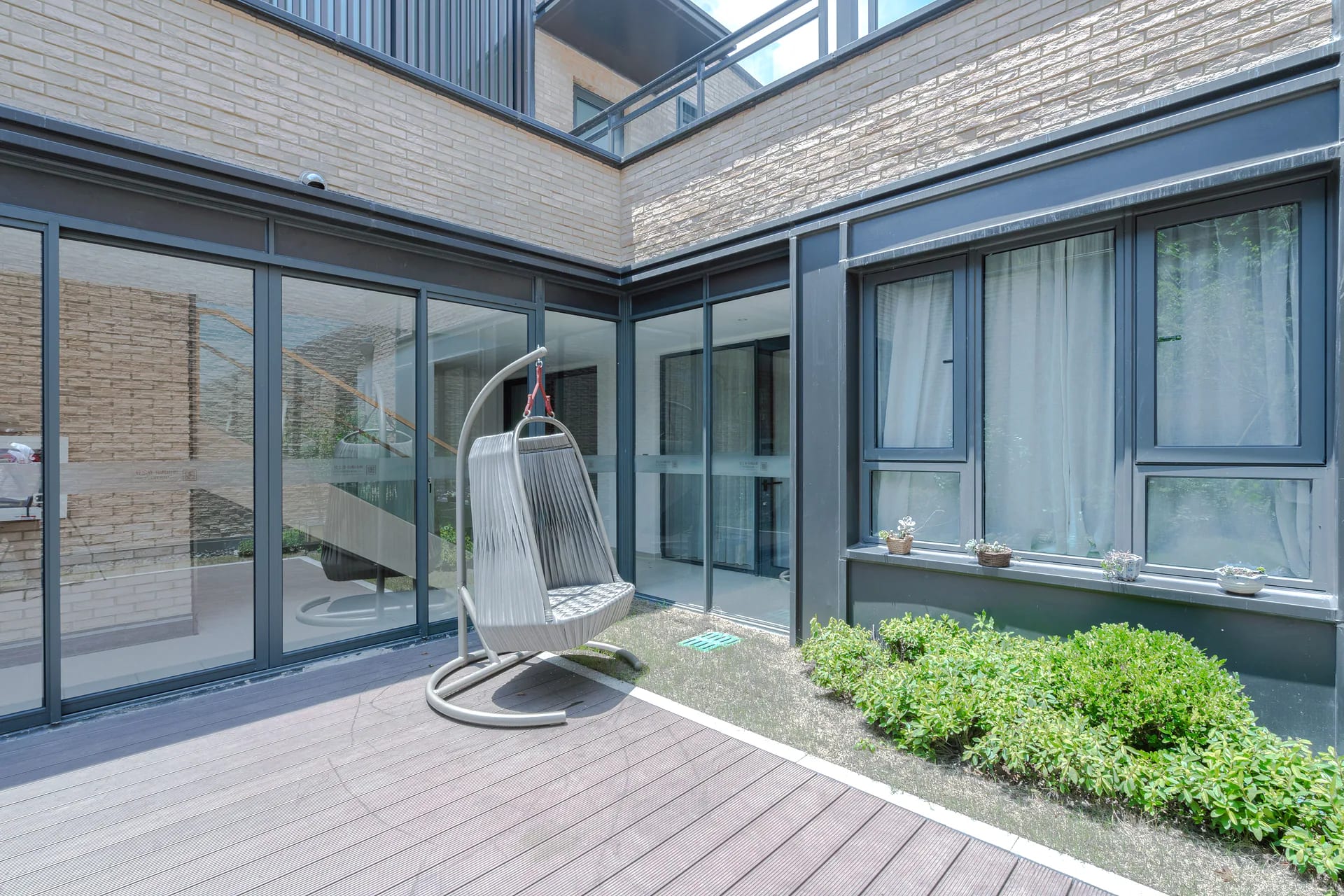 Antraciet schuifpui op de hoek van een terras, met slanke kaders en zicht naar de tuin