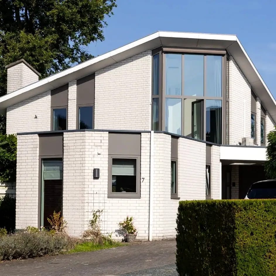 Vrijstaande Nederlandse gezinswoning met lichte baksteen en antraciet kozijnen, inclusief een glazen hoekpui