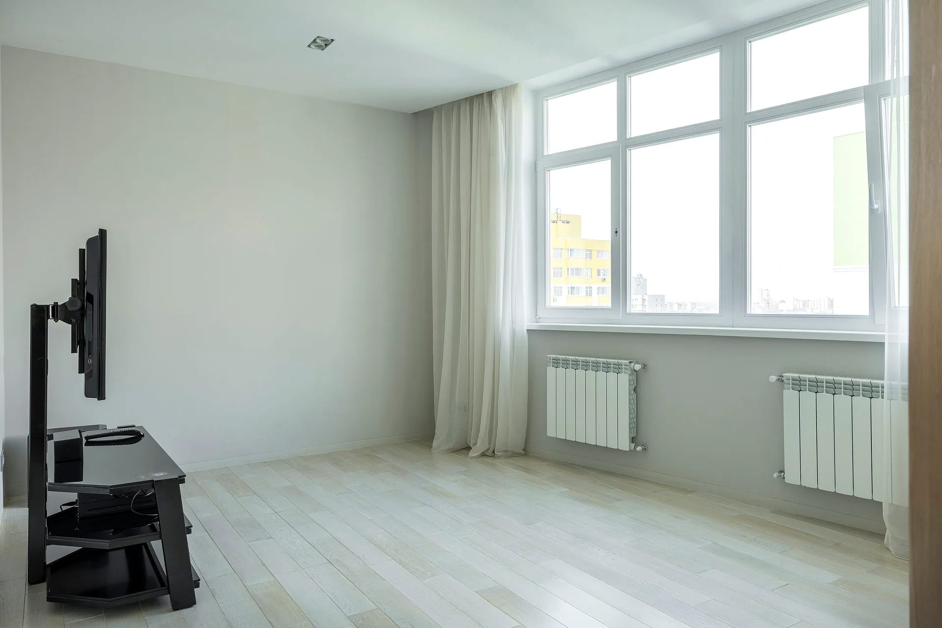 Close-up van een wit raam met zichtbare greep en isolerend glas, uitkijkend op een woonwijk