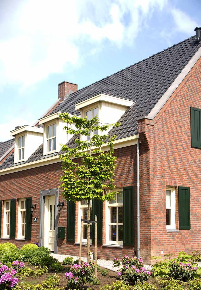 Bakstenen gezinswoning met witte kunststof kozijnen, dakkapel en voortuin — herkenbare Nederlandse woonsituatie