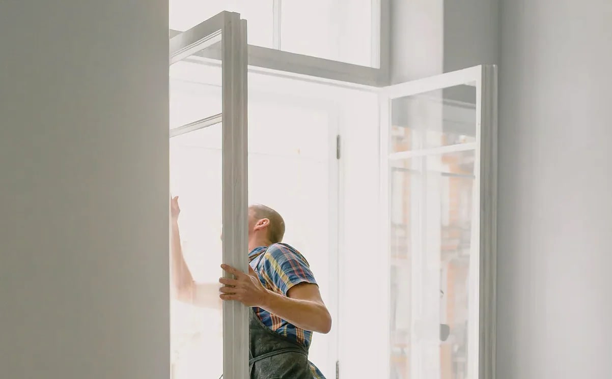 Openstaand raam met zichtbare vleugel in een woning, met bakstenen straatbeeld op de achtergrond