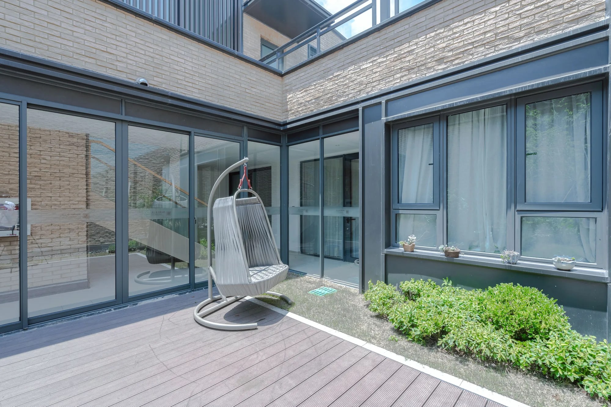 Achtergevel met antraciet deuren en kozijnen naar een houten terras en tuin