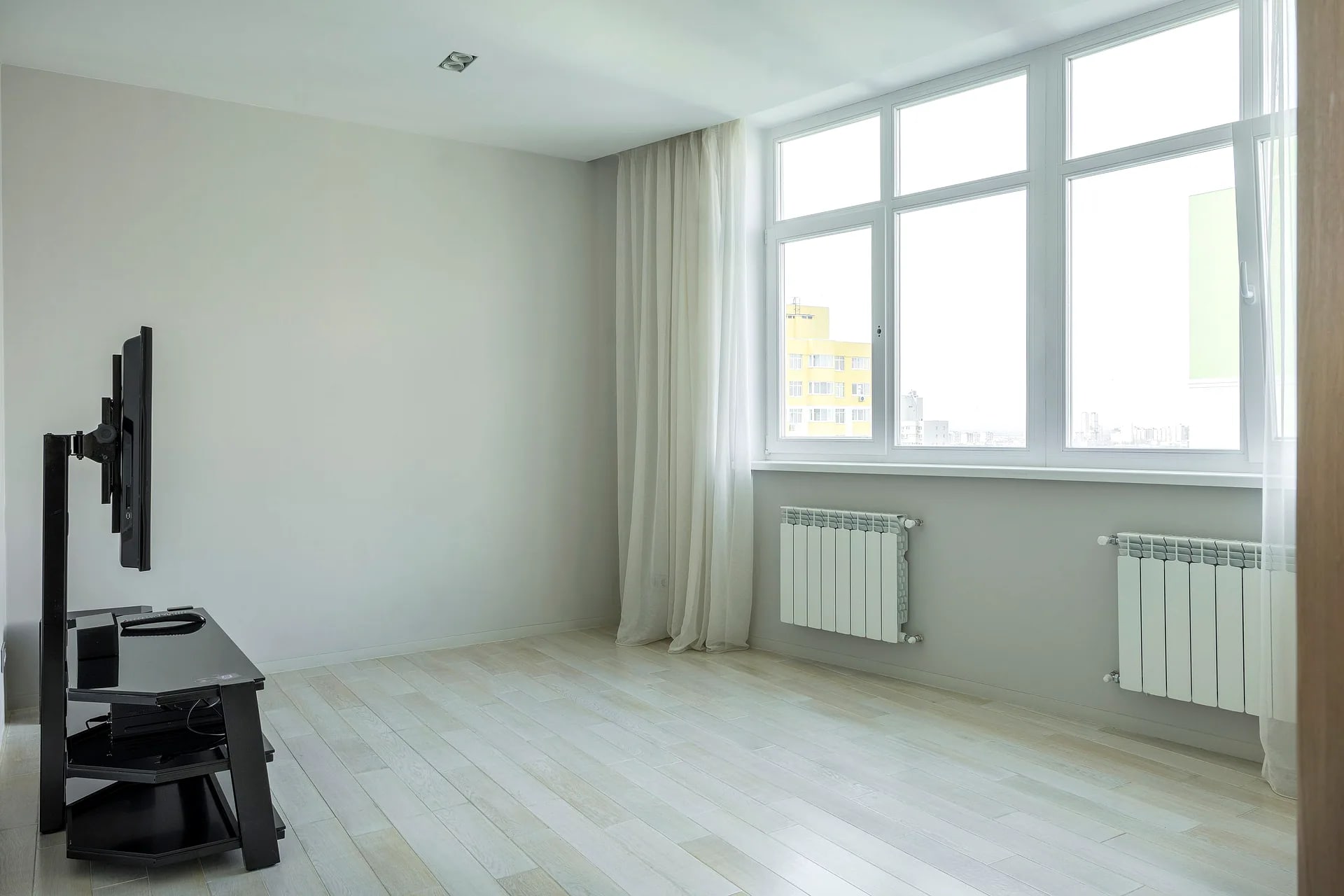 Witte kozijnen met zichtbare raamgreep in een appartement, met uitzicht op een woonwijk